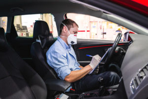 technician sitting in car checklisting wearing protective gloves and mask